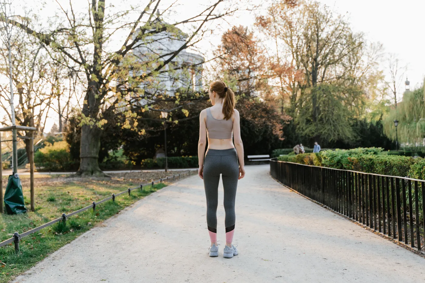 Woman walking along a sunny park path in activewear