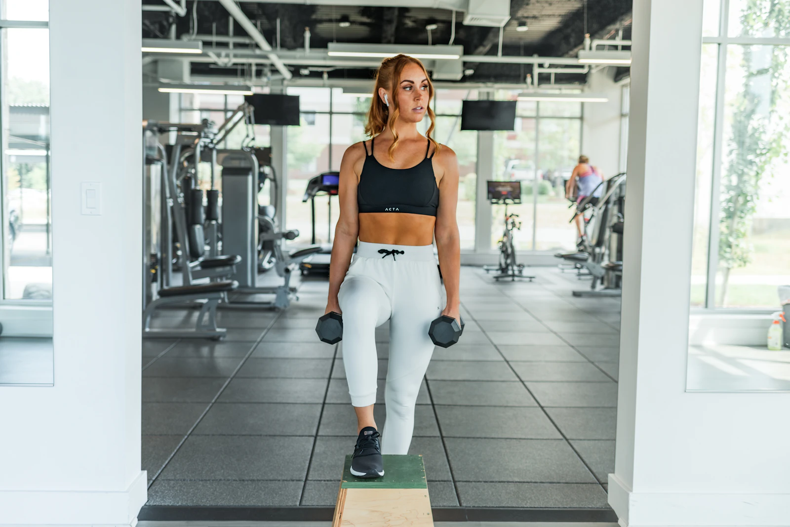 Woman carrying dumbbells in a gym strength-training area