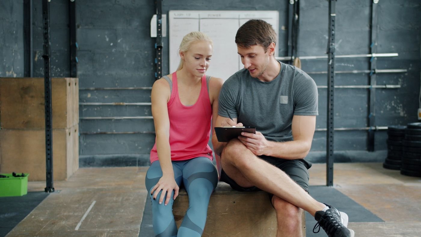 Personal trainer discussing an exercise plan with a gym client