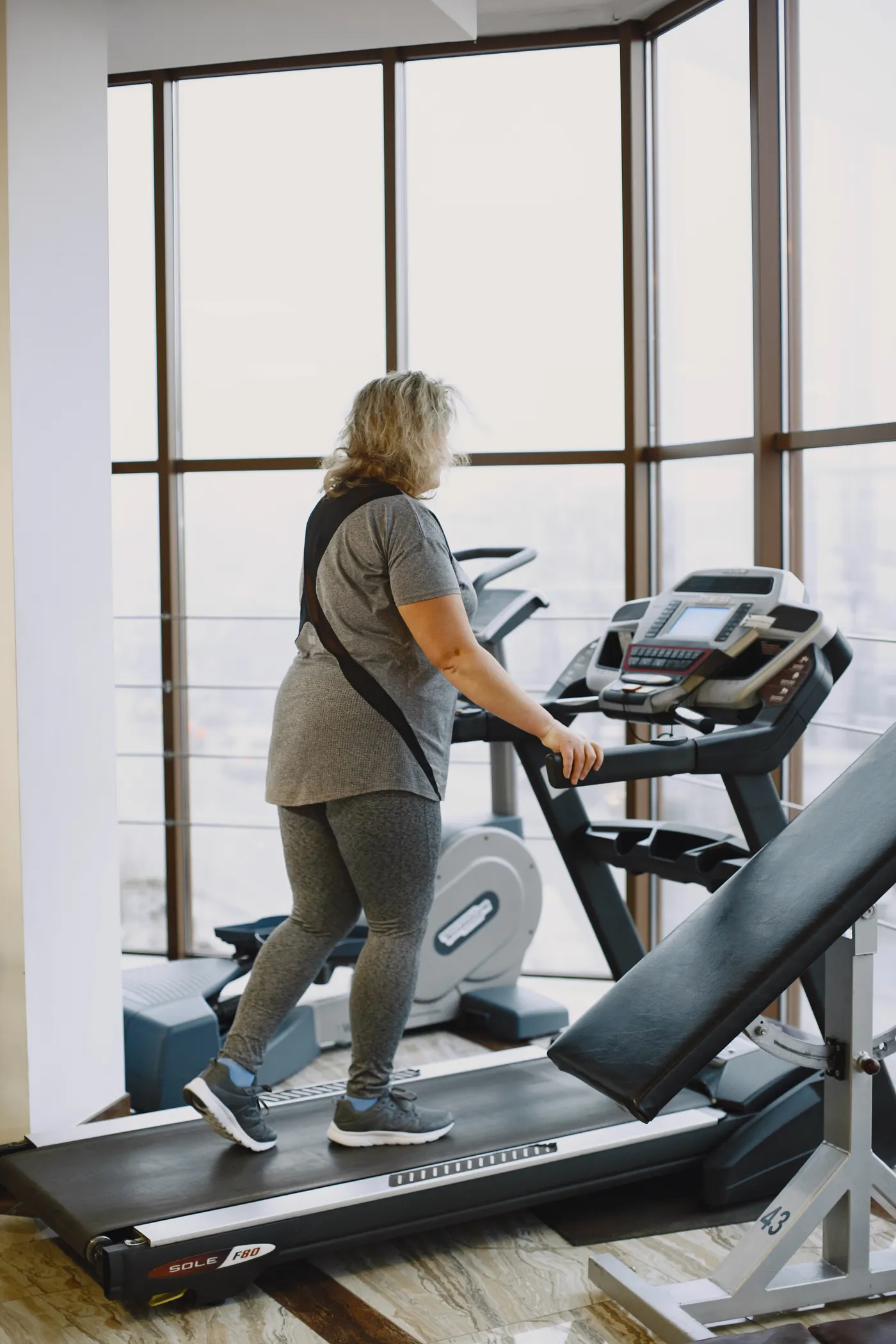 Mature woman walking on a treadmill in a bright gym