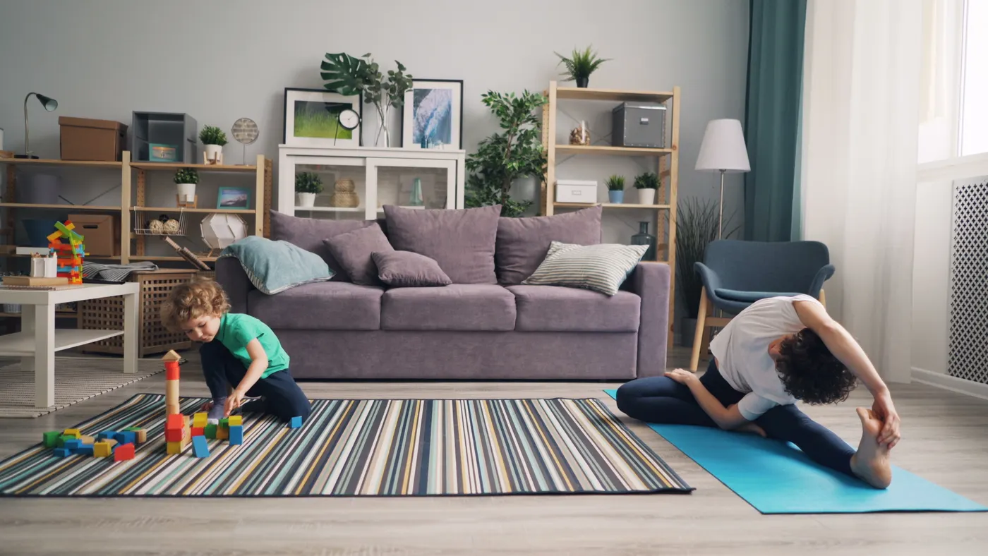 Mother exercising on a mat while her son plays