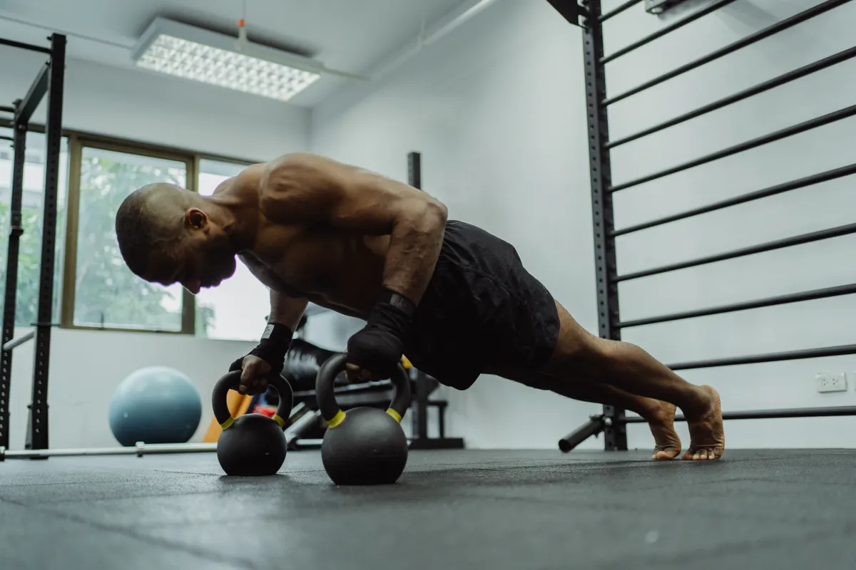 Man performing a controlled push-up using kettlebell handles