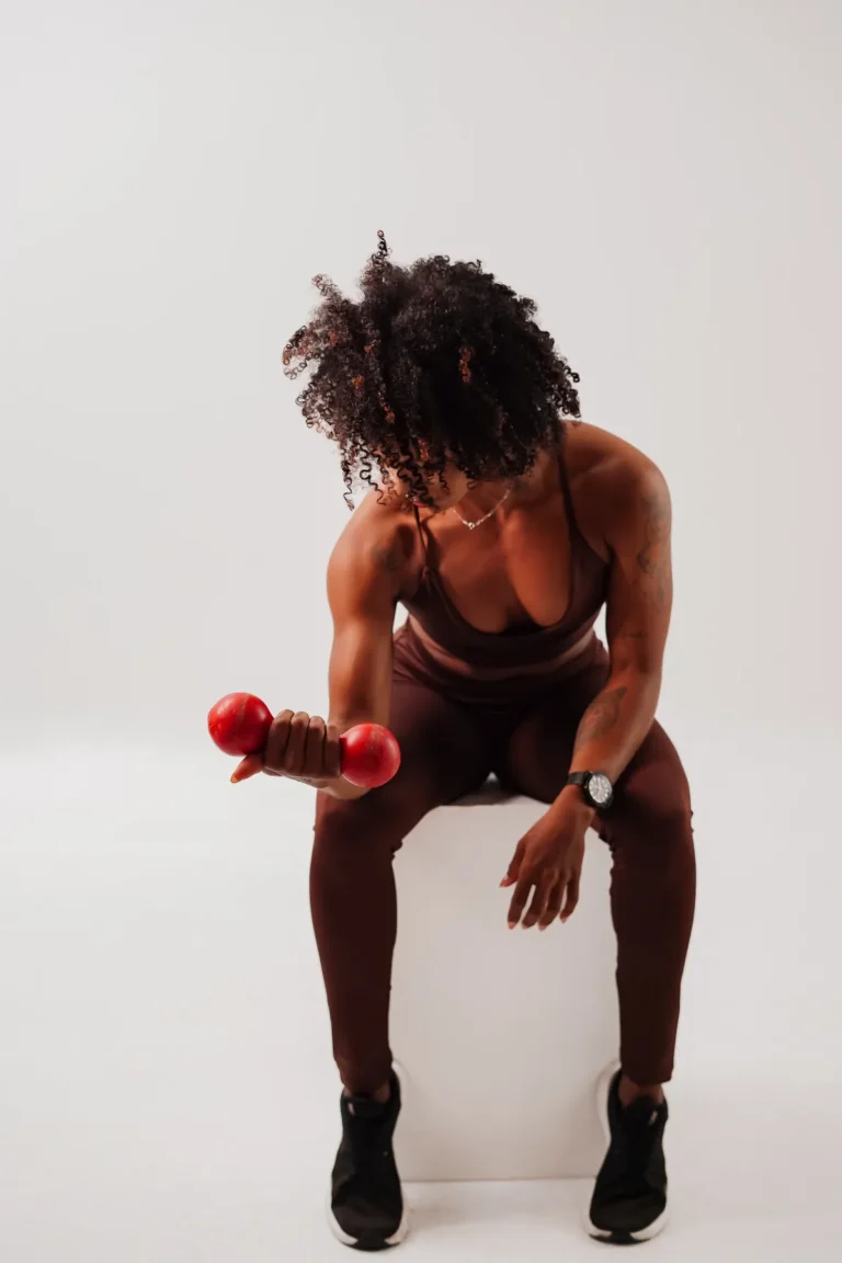 Athlete performing a seated dumbbell curl with a red weight
