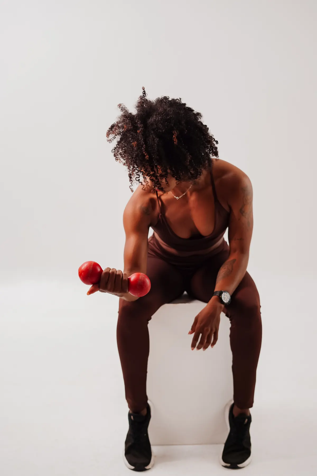 Athlete performing a seated dumbbell curl with a red weight