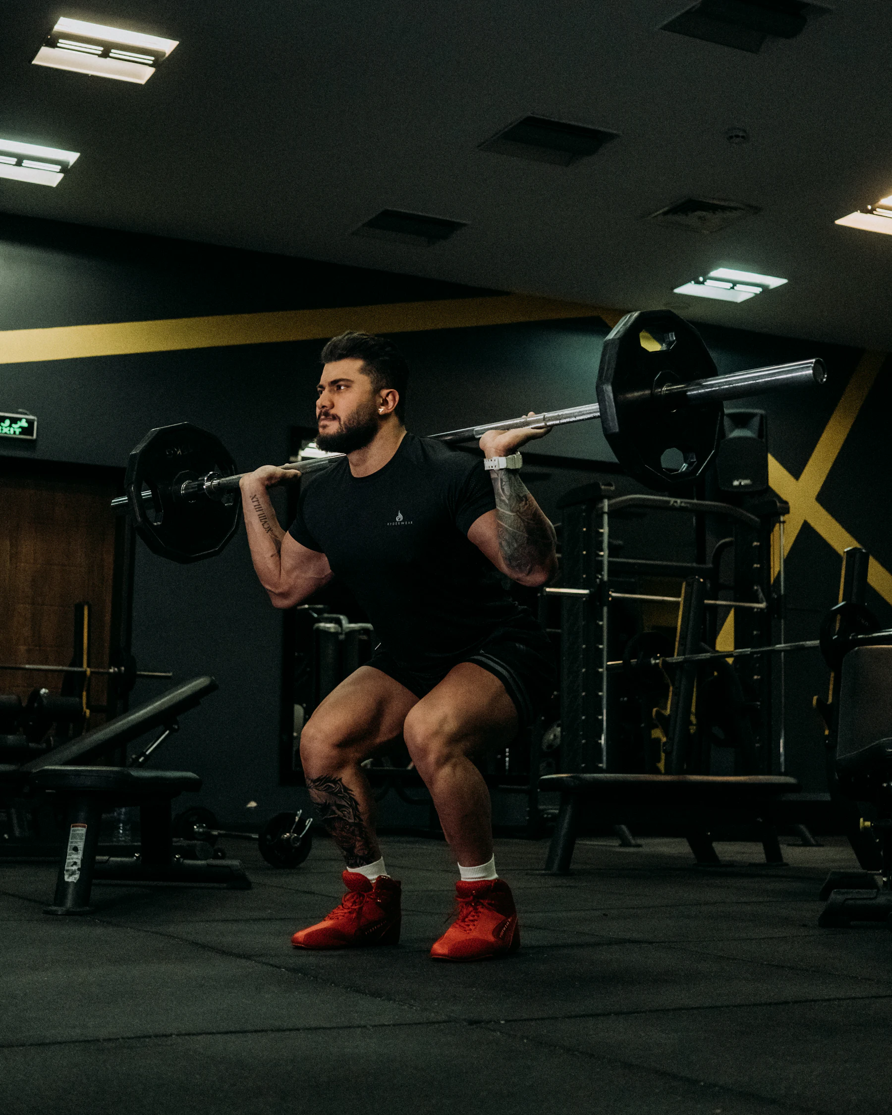Man positioning a loaded barbell for a squat in a gym