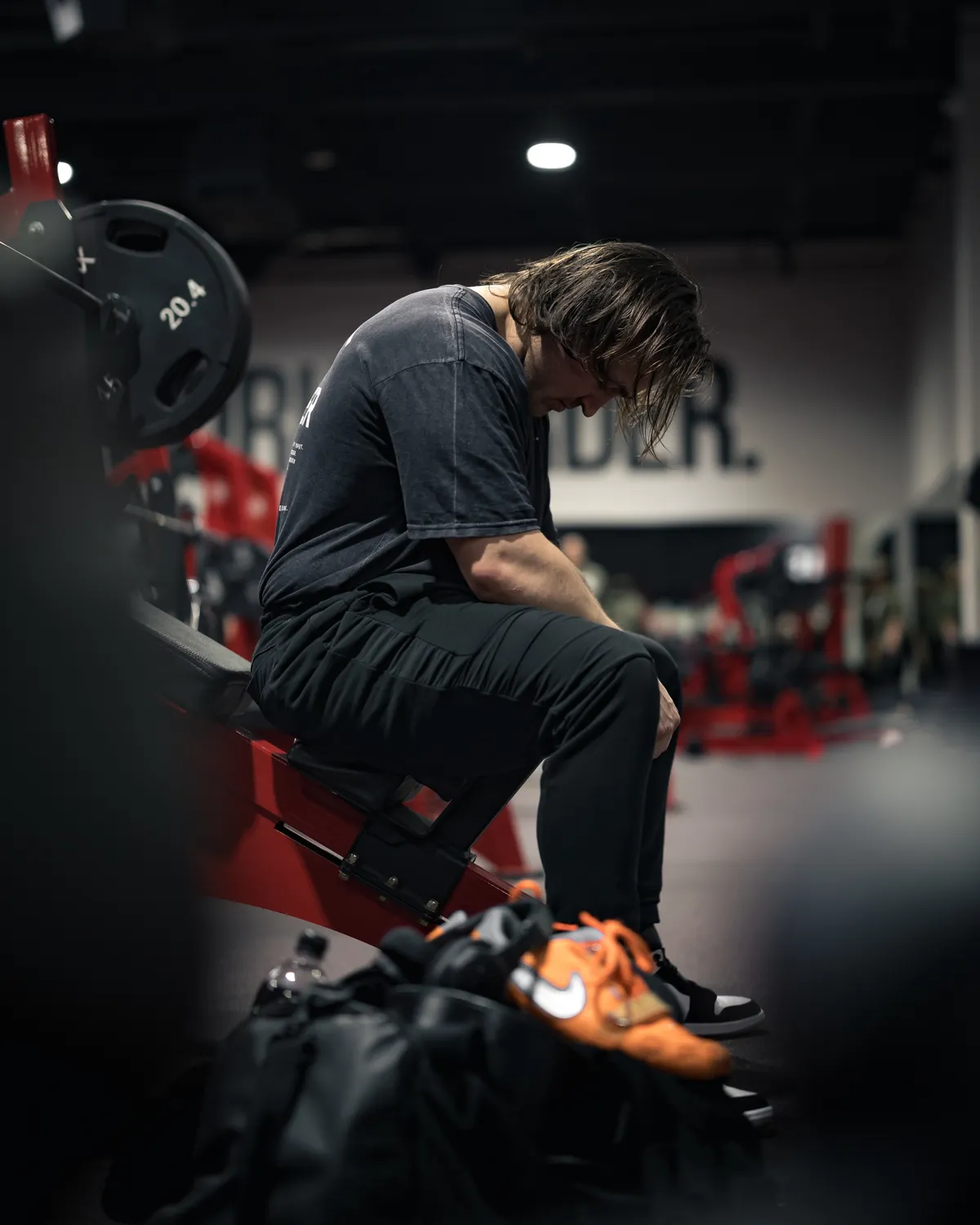 Man sitting on a gym bench during recovery between training efforts