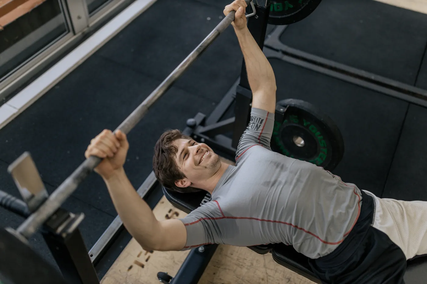 Man completing a bench press repetition in a gym