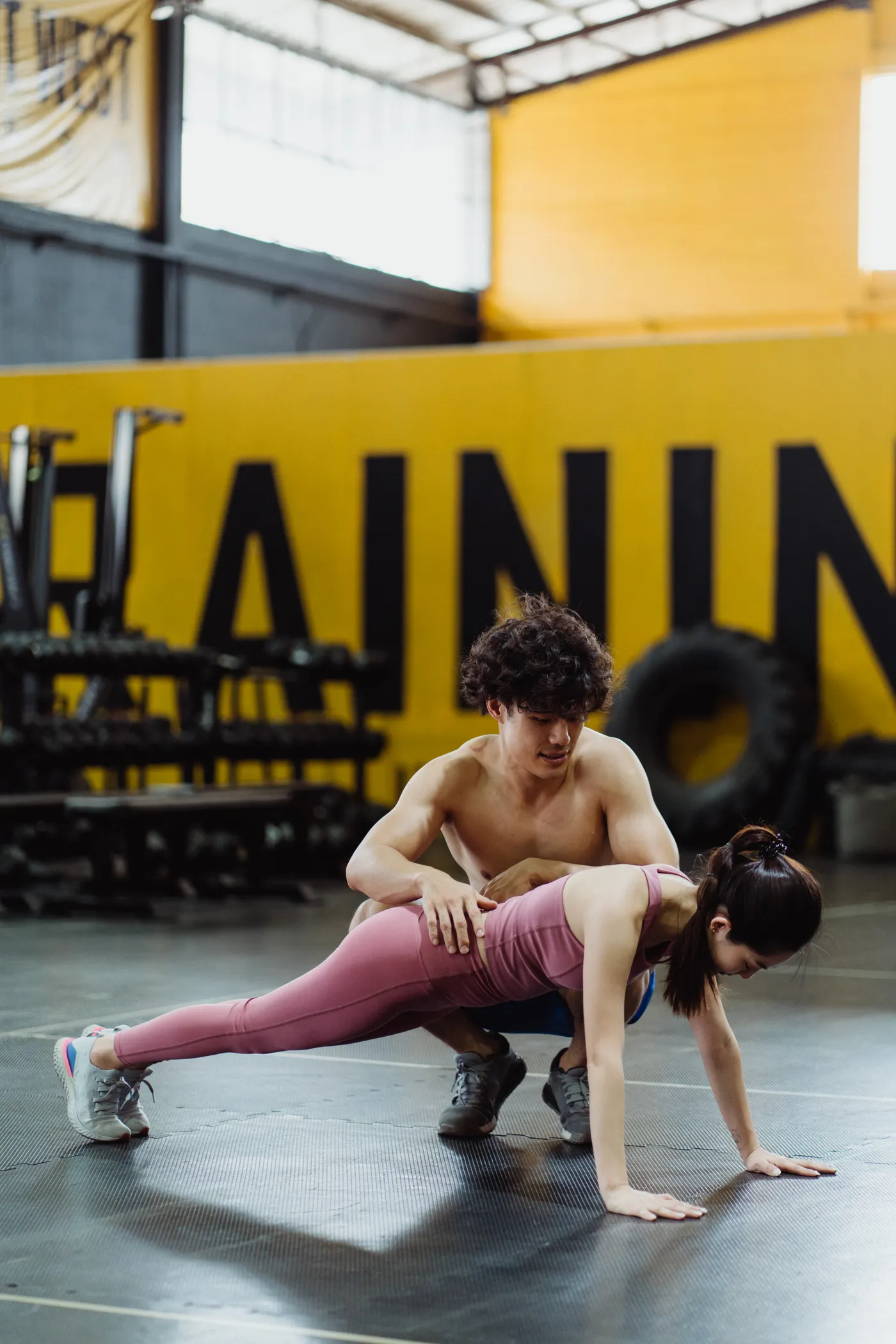 Woman practicing a push-up with a trainer in a gym
