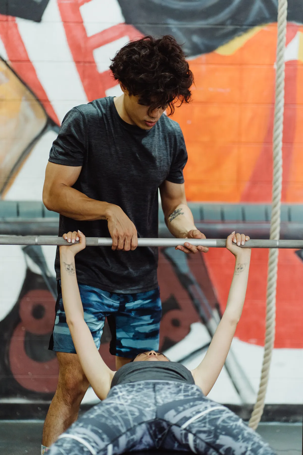 Trainer assisting a woman during a barbell strength-training session