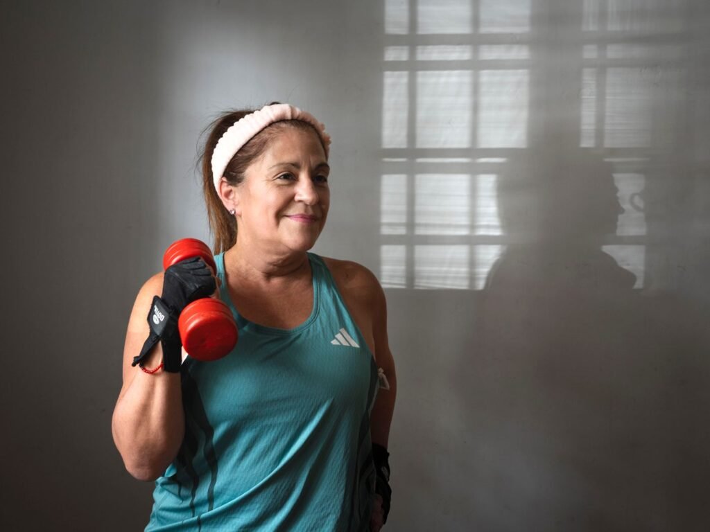 Active senior woman training with dumbbells indoors