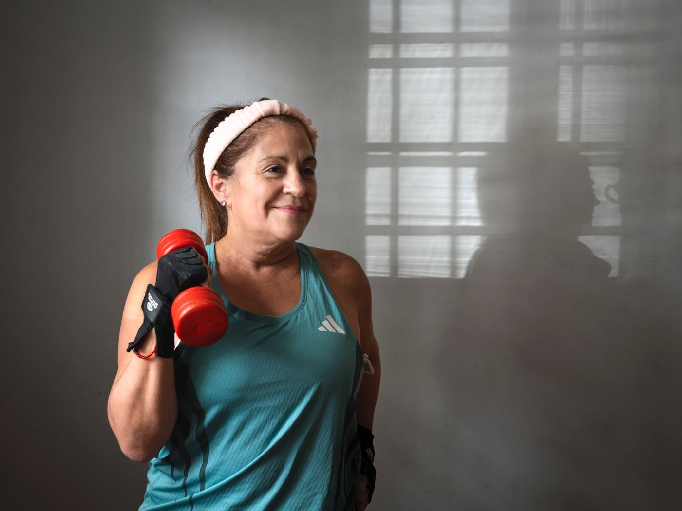 Active senior woman training with dumbbells indoors