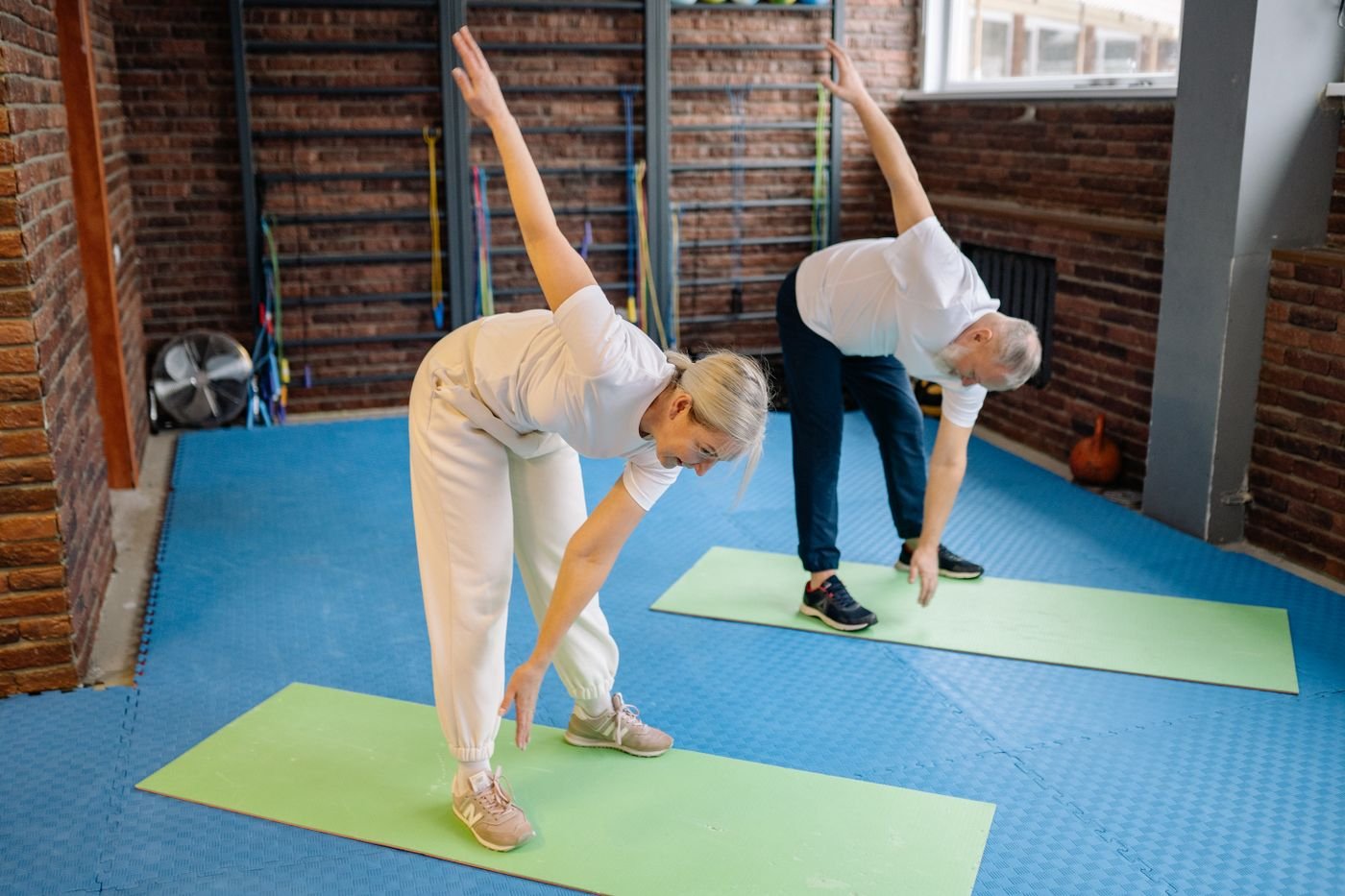Older couple doing gentle stretching exercises on mats