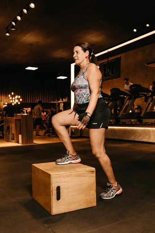 Woman performing a step-up onto a sturdy box in a gym
