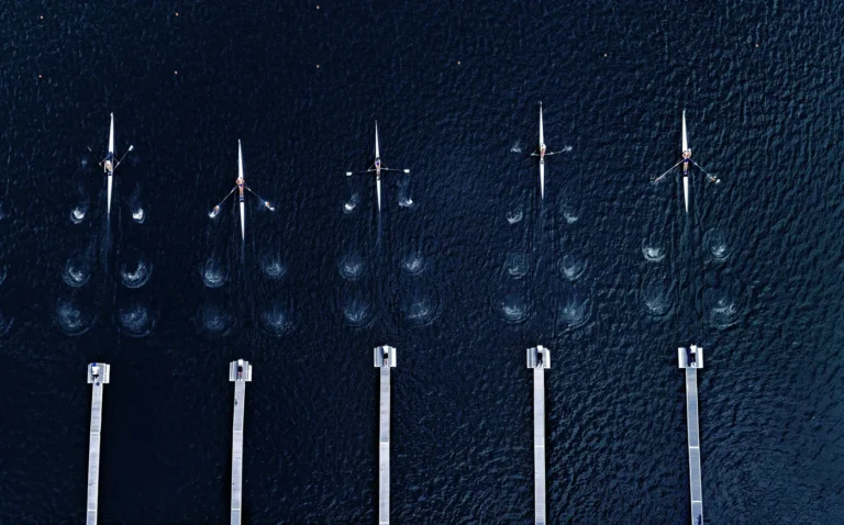 Aerial view of a rowing crew moving in sync across a calm lake