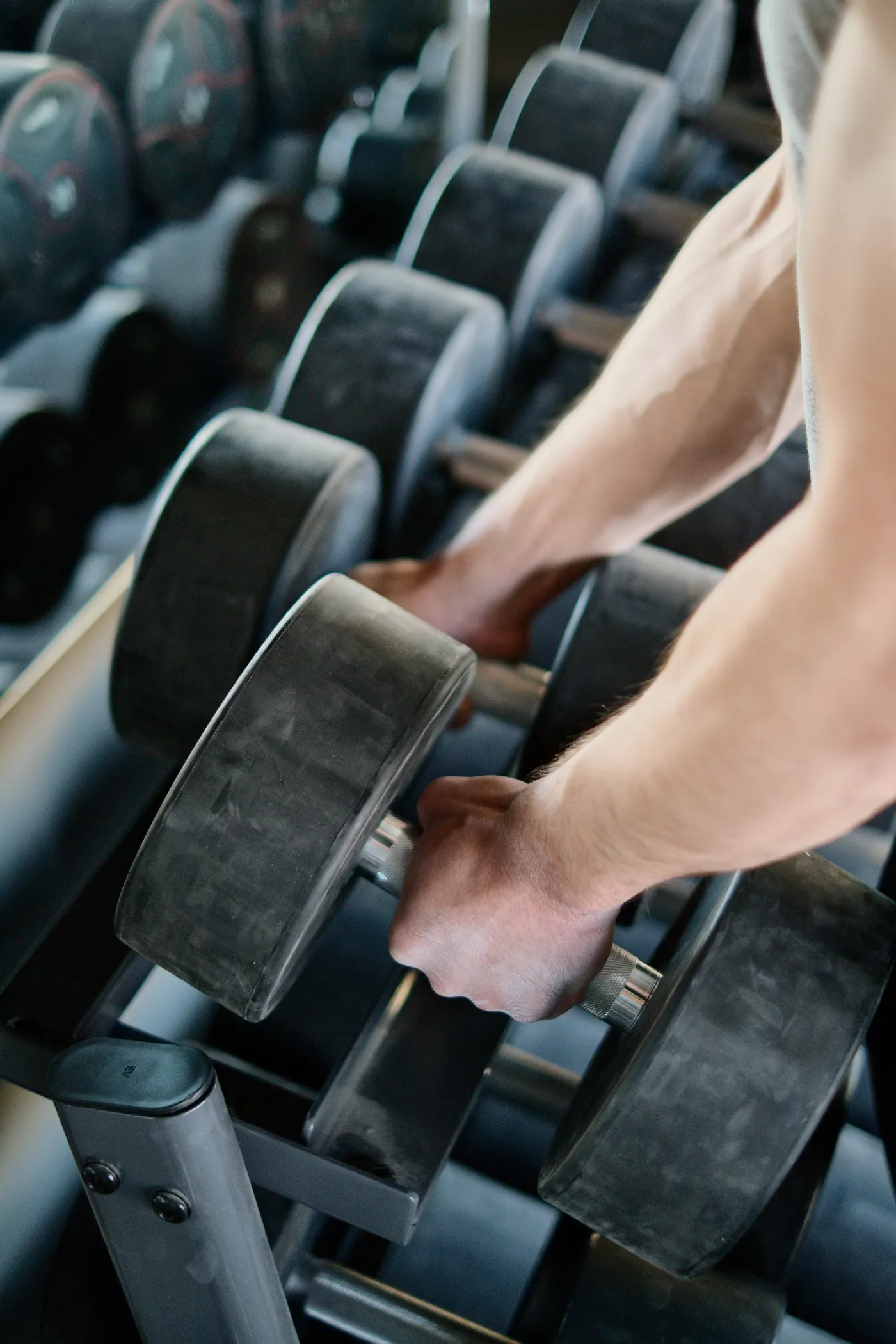 Person selecting dumbbells from a weight rack