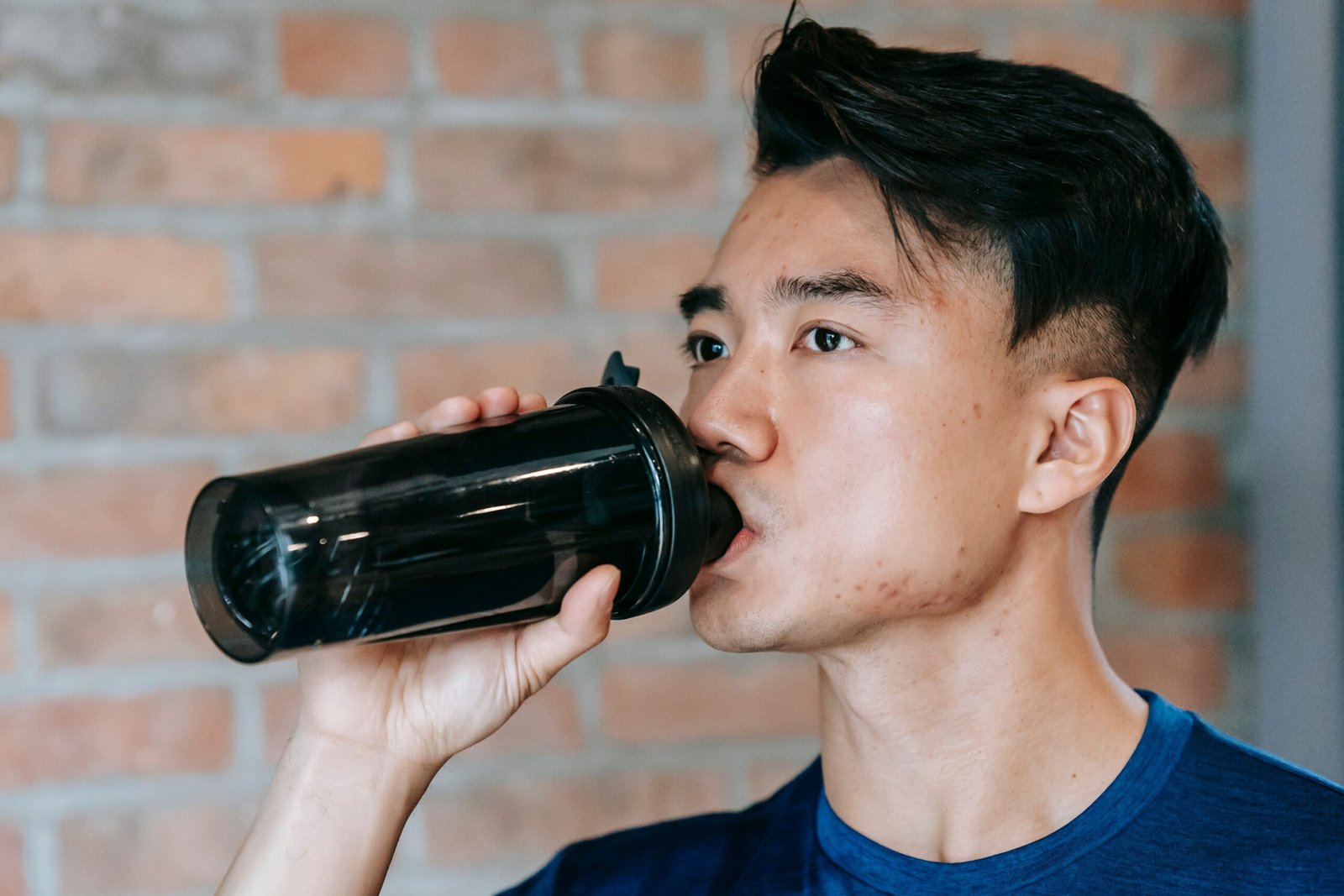 Athlete drinking from a shaker bottle between gym sets
