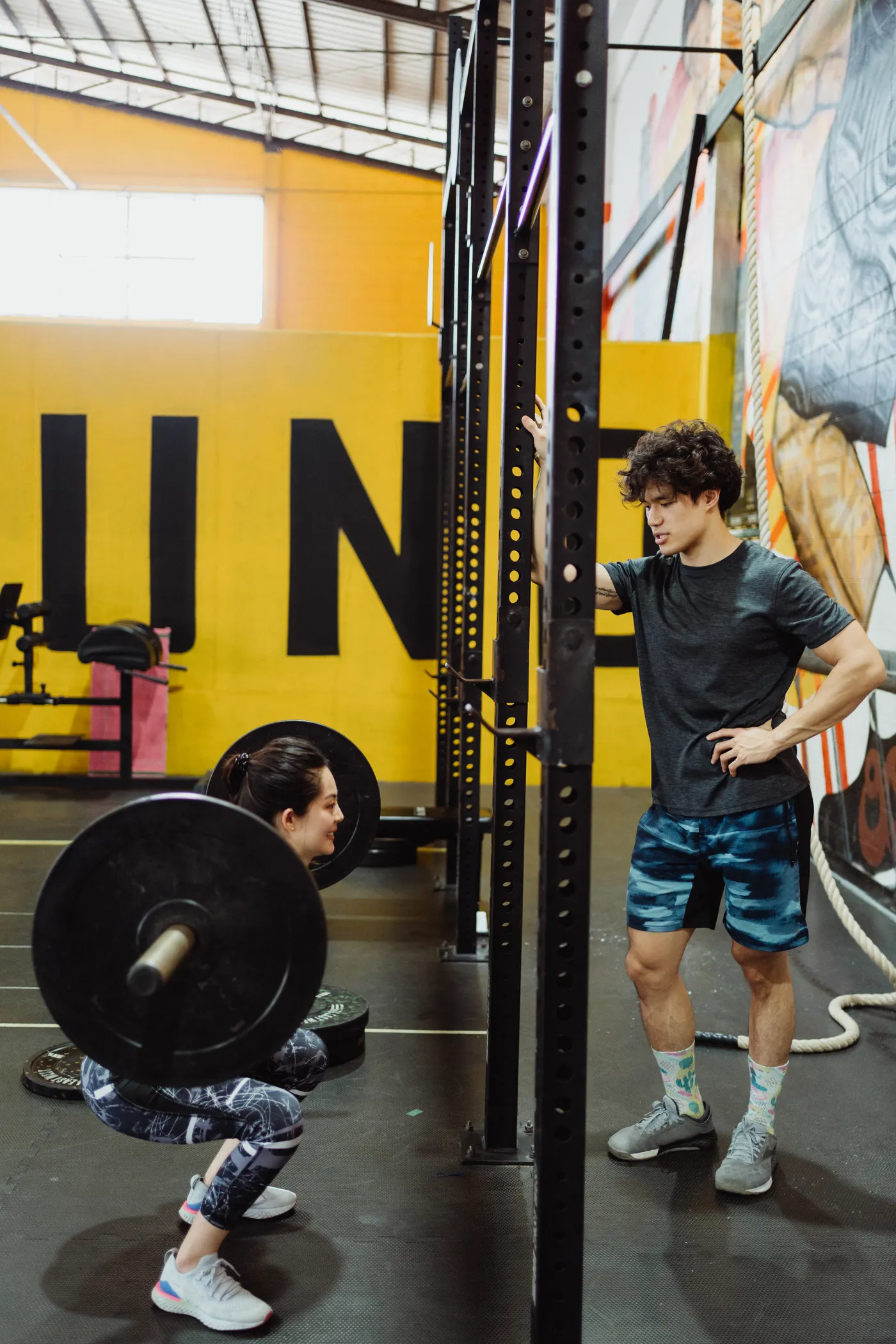 Trainer supervising a woman during a barbell squat