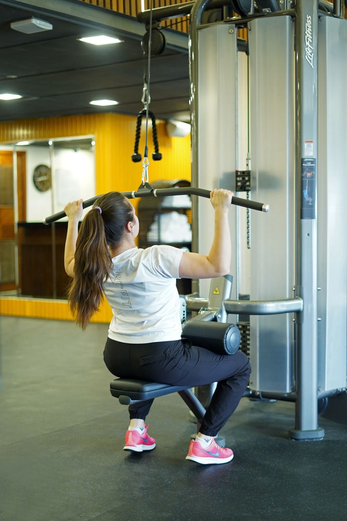 Woman performing a controlled lat pulldown in a gym