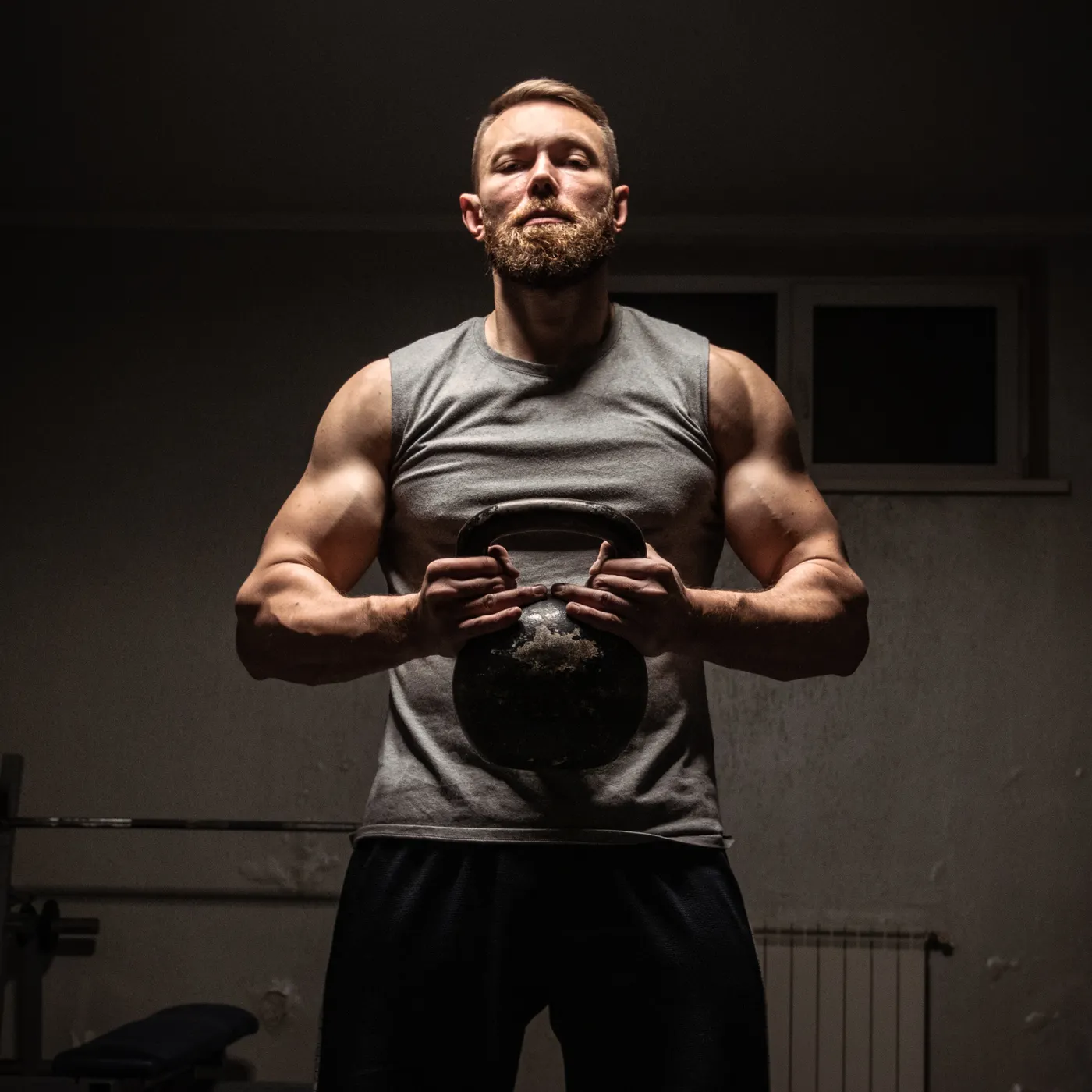 Strong athlete lifting a kettlebell inside a gym