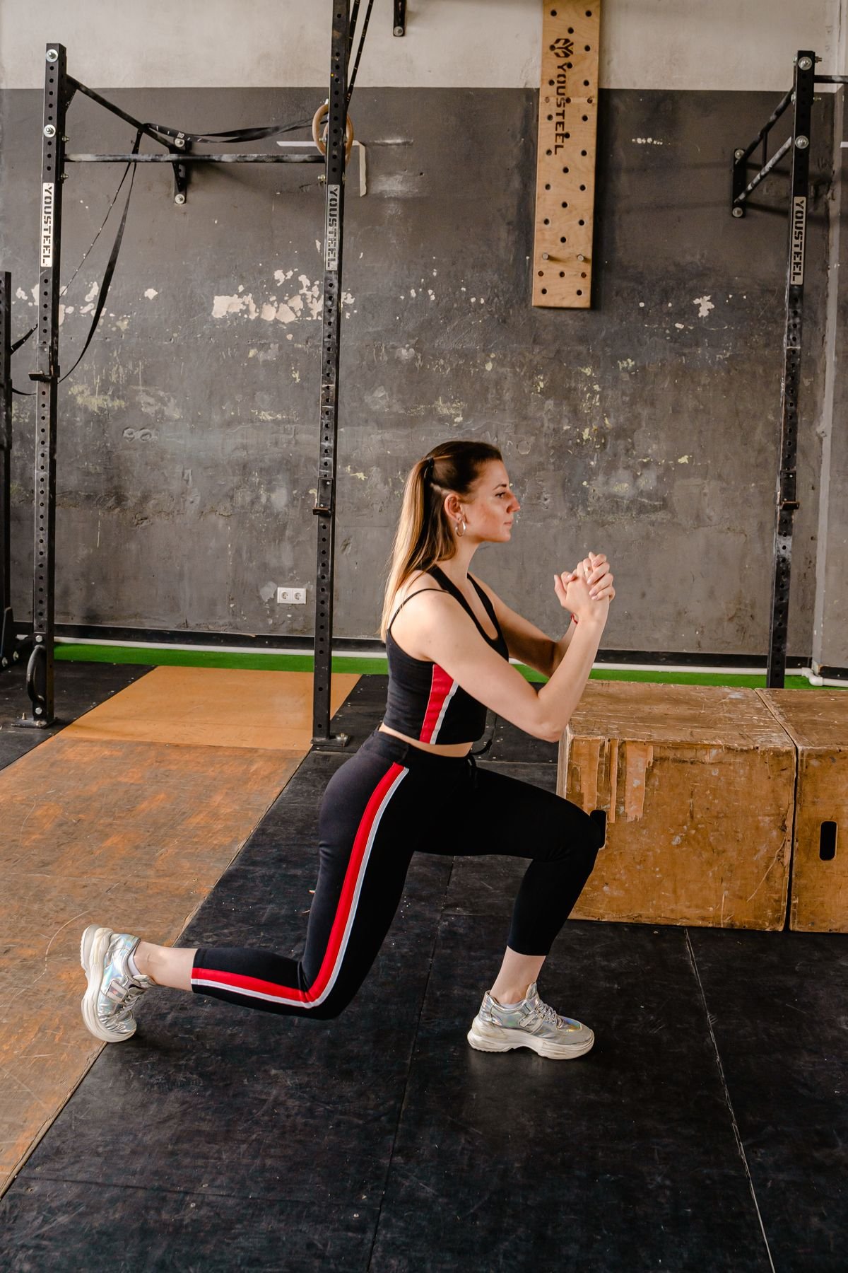 Woman demonstrating a bodyweight lunge in a gym