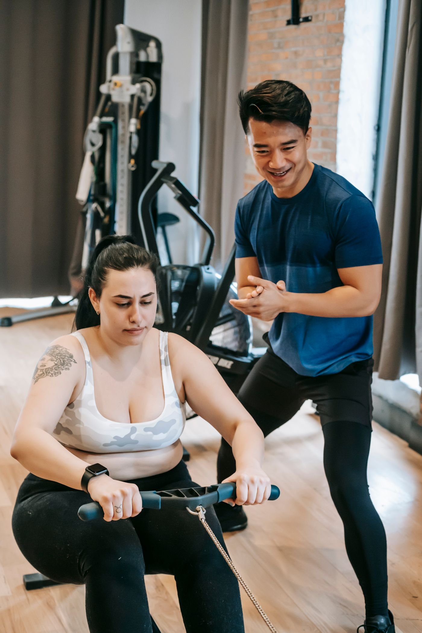 Trainer assisting a woman during a rowing workout
