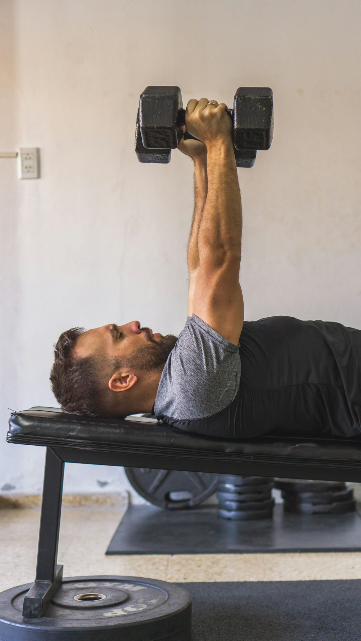 Lifter pressing a dumbbell on a weight bench