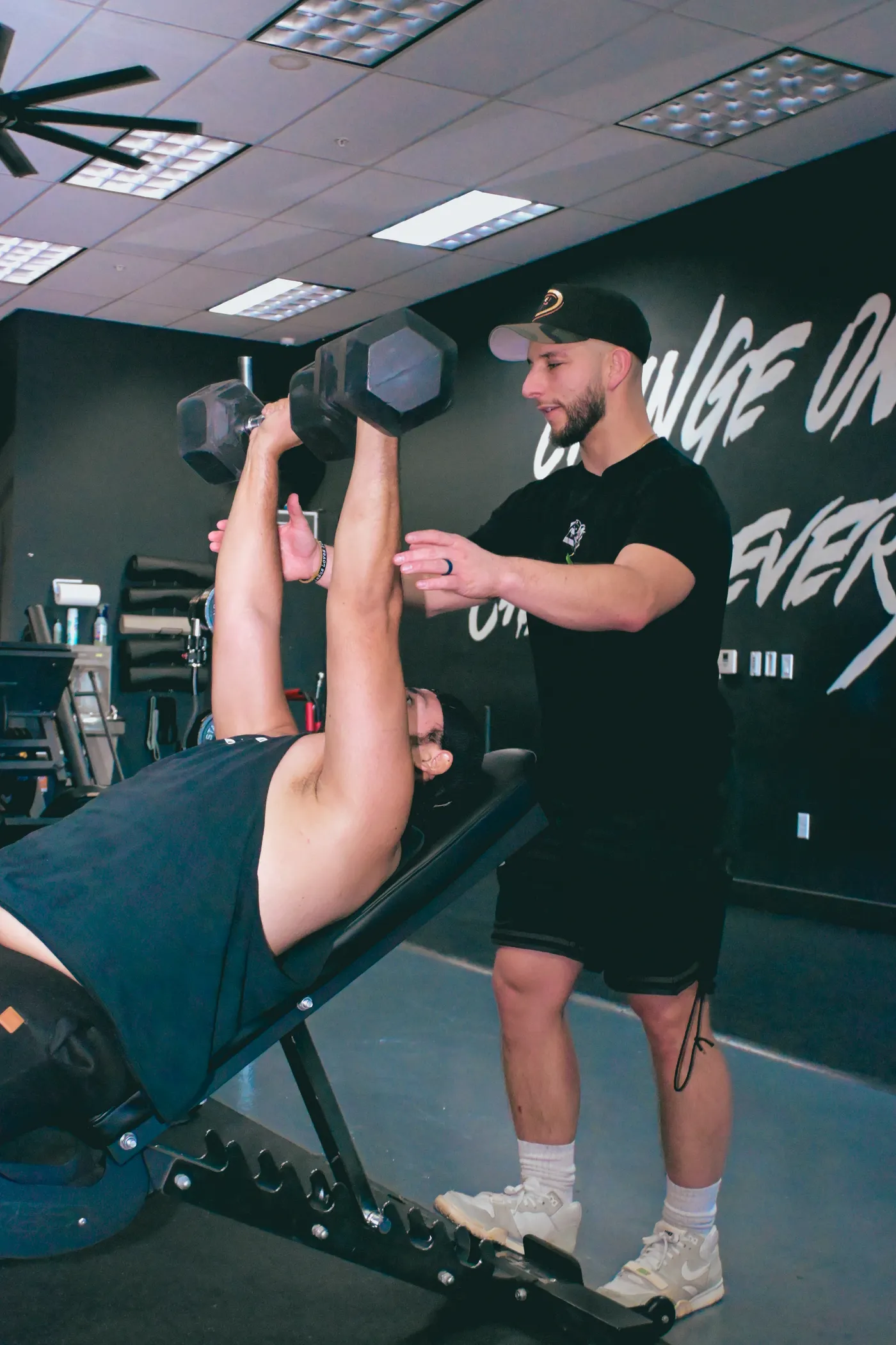 Coach assisting a lifter with dumbbell technique