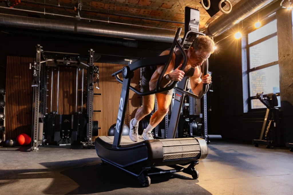Athlete performing a heavy sled push on the REP Strive Curved Treadmill
