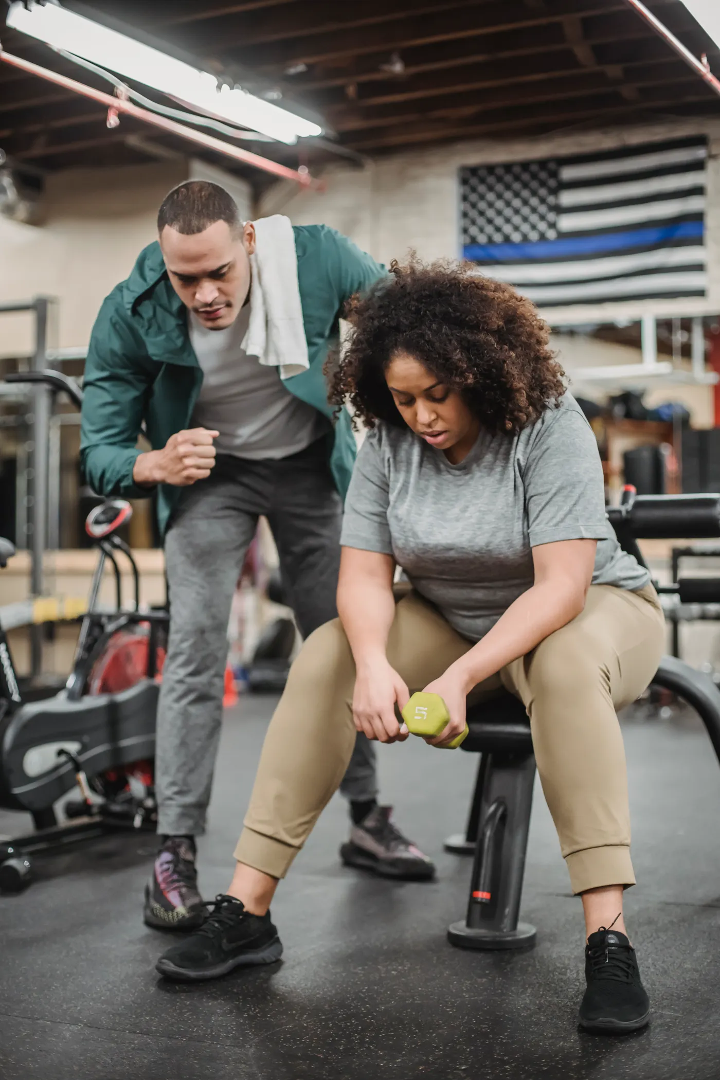 Personal trainer guiding a woman during a dumbbell exercise