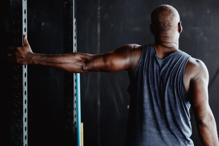Man stretching an arm in a gym after training