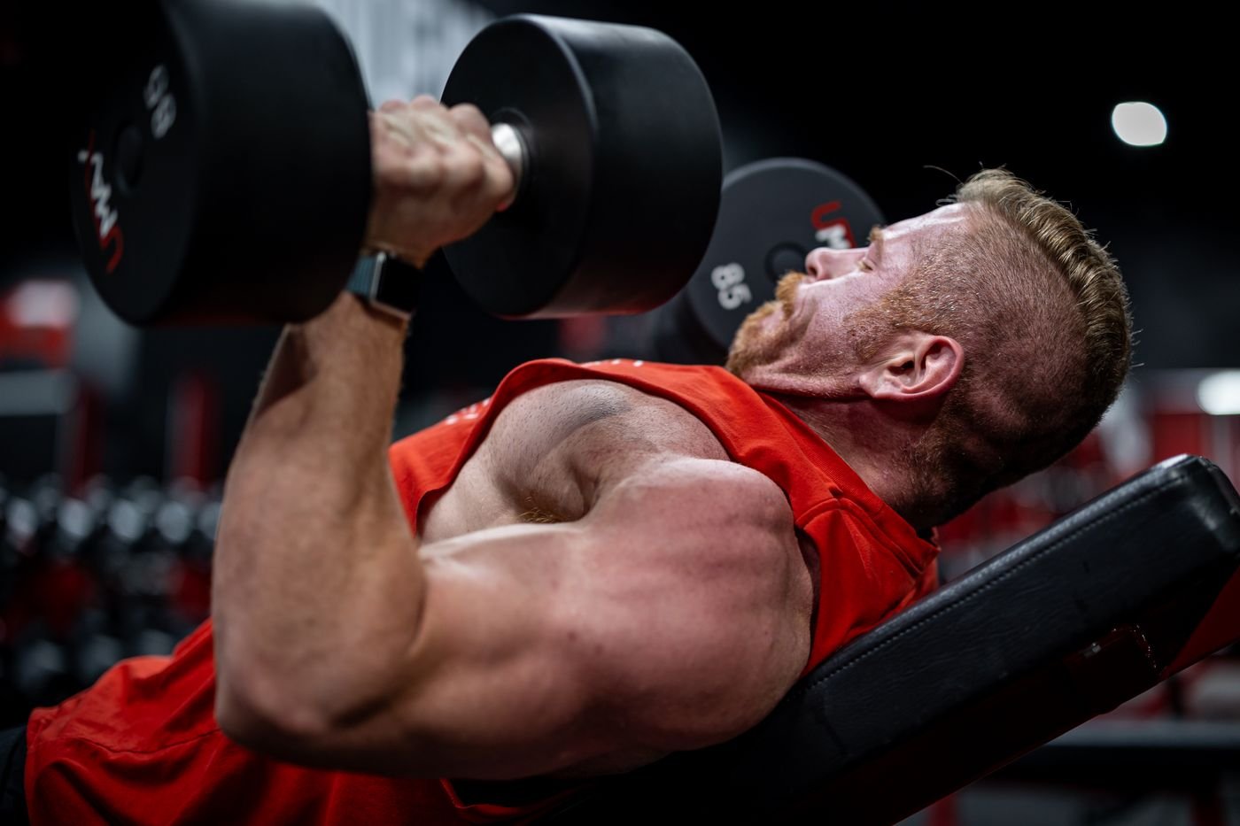 Man lifting dumbbells on a weight bench during upper-body training