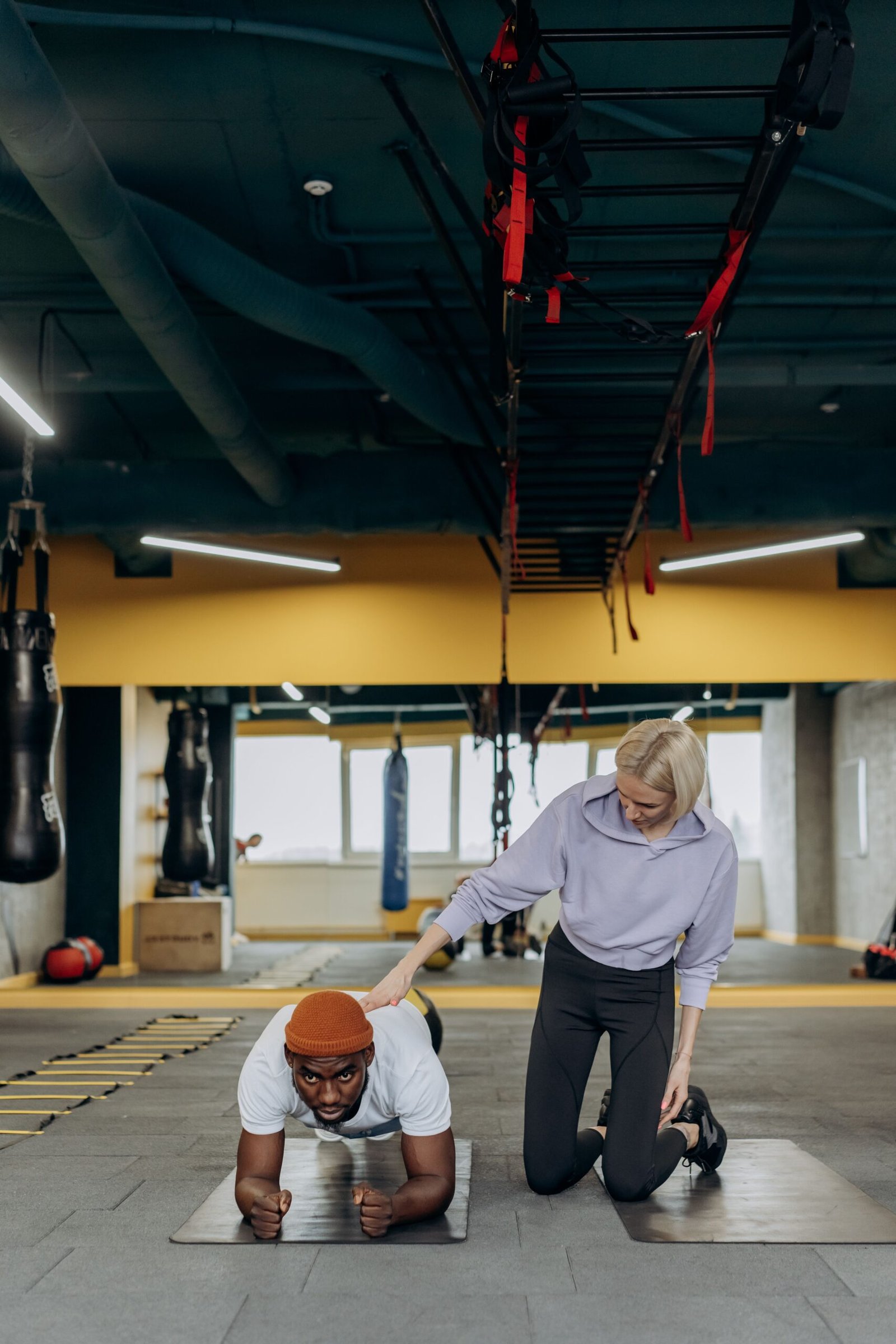 Coach guiding a man through a plank in a training studio