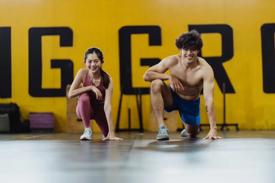 Two athletes stretching together in a gym