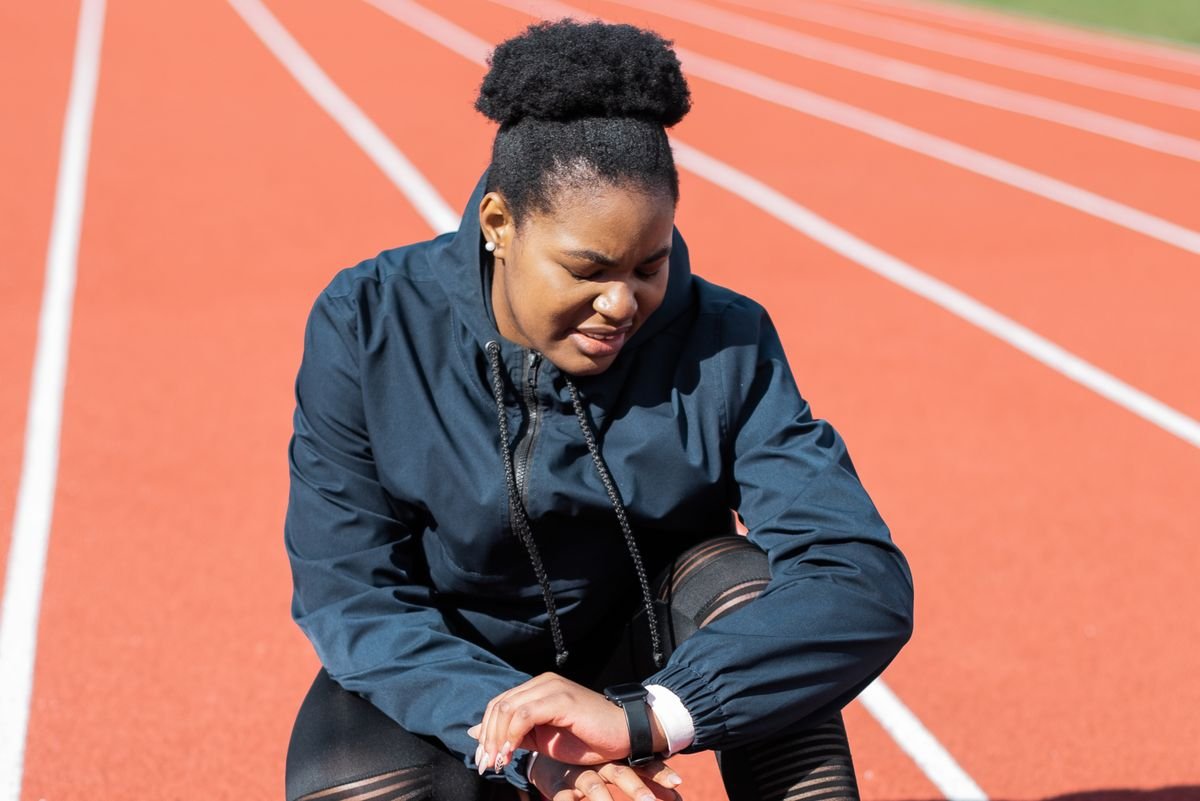 Runner checking her smartwatch on an outdoor running track
