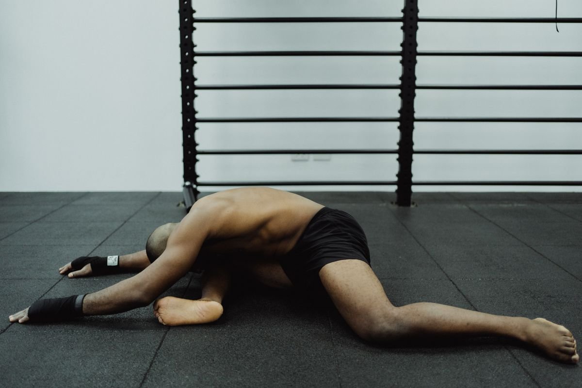 Man seated on a gym floor performing a hamstring stretch