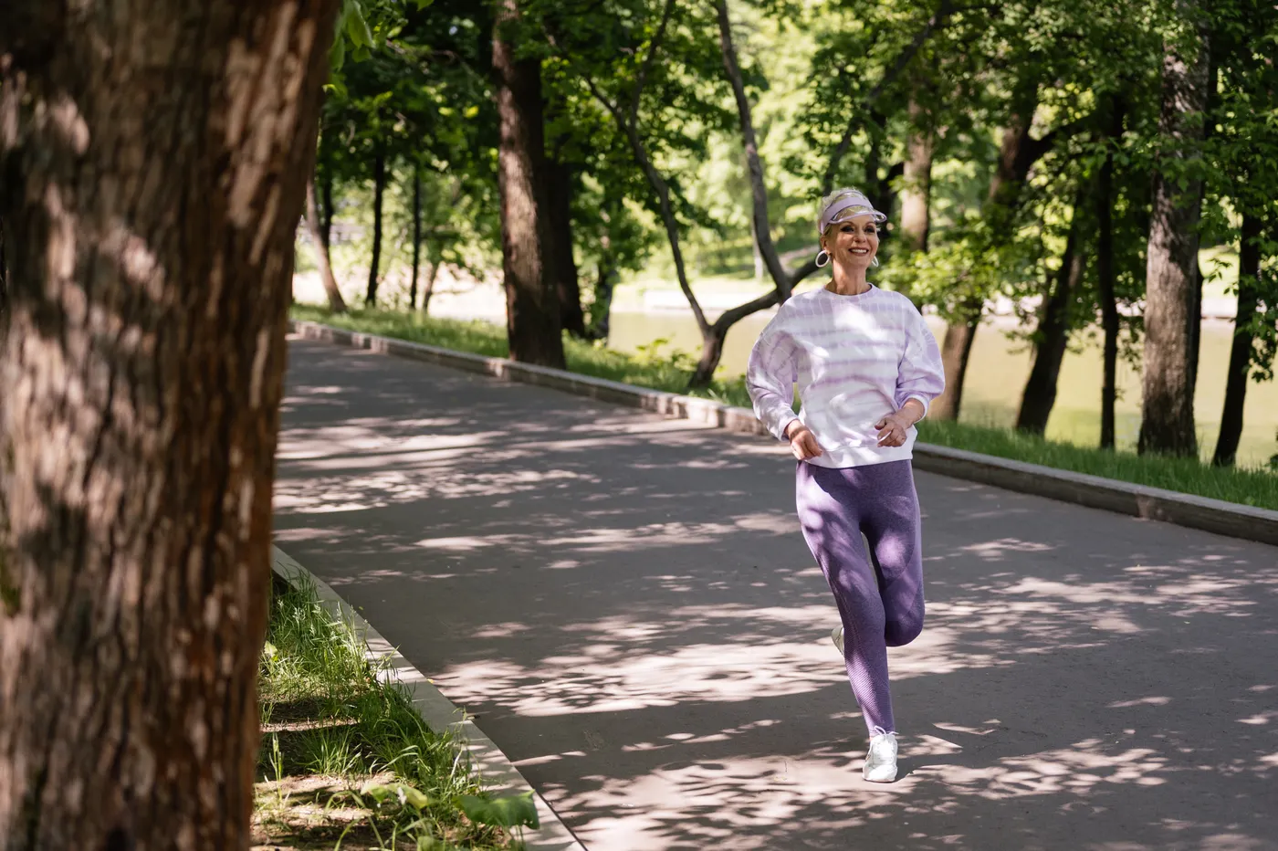 Older woman moving at a lively pace along a green outdoor trail