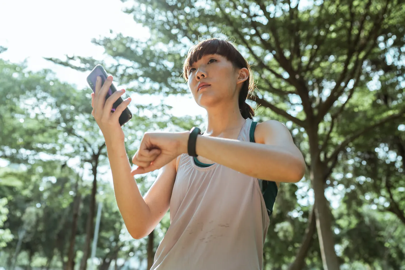 Woman connecting her phone to a smartwatch during a workout break