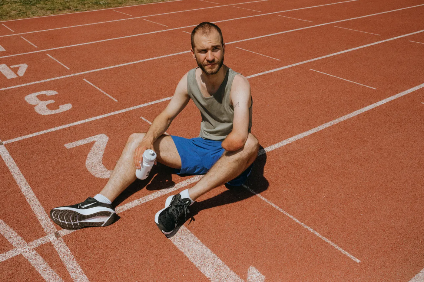 Runner taking a break on a track with a water bottle