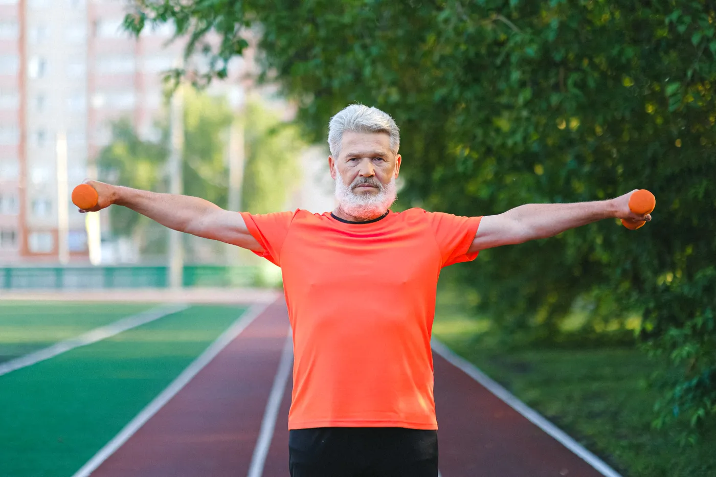 Older man lifting dumbbells during outdoor exercise