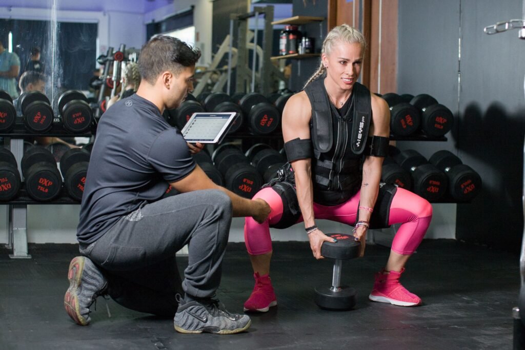 Coach guiding a woman through a dumbbell squat