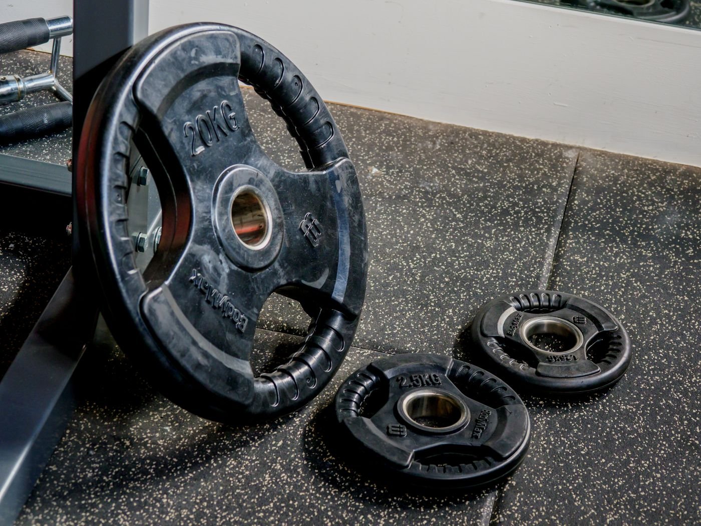 Black weight plates on the floor of a strength-training gym