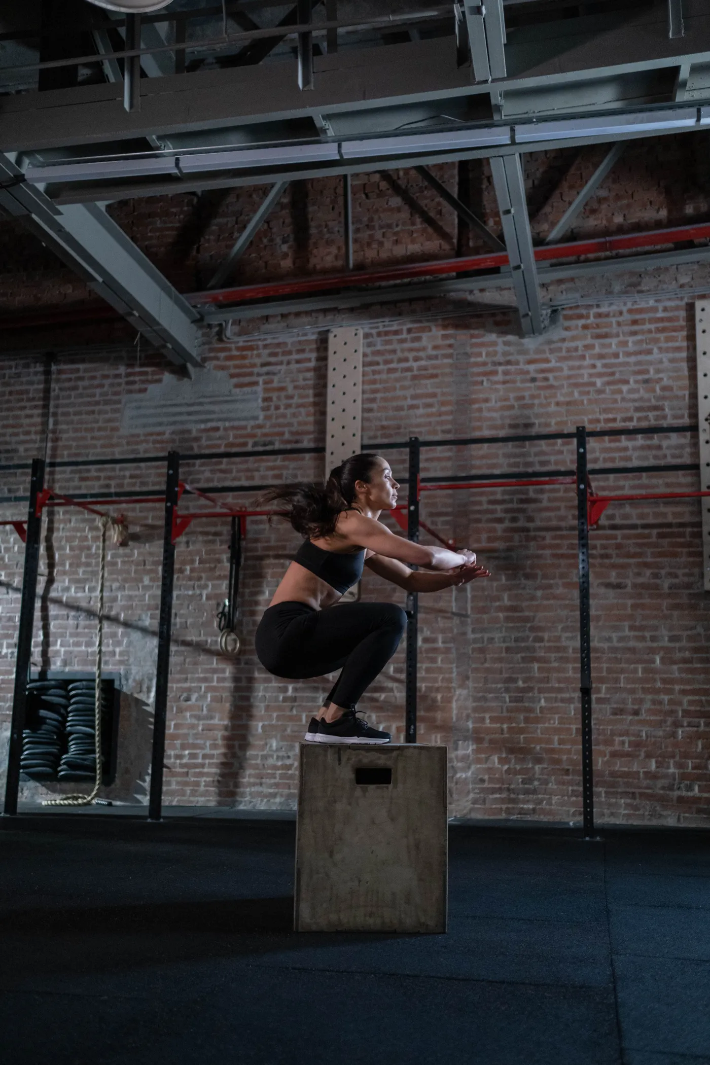 Woman practicing a plyometric box jump in a gym