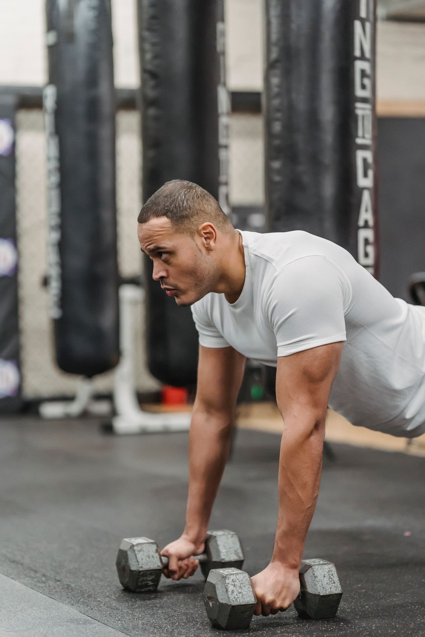 Man maintaining a plank with dumbbells in a gym