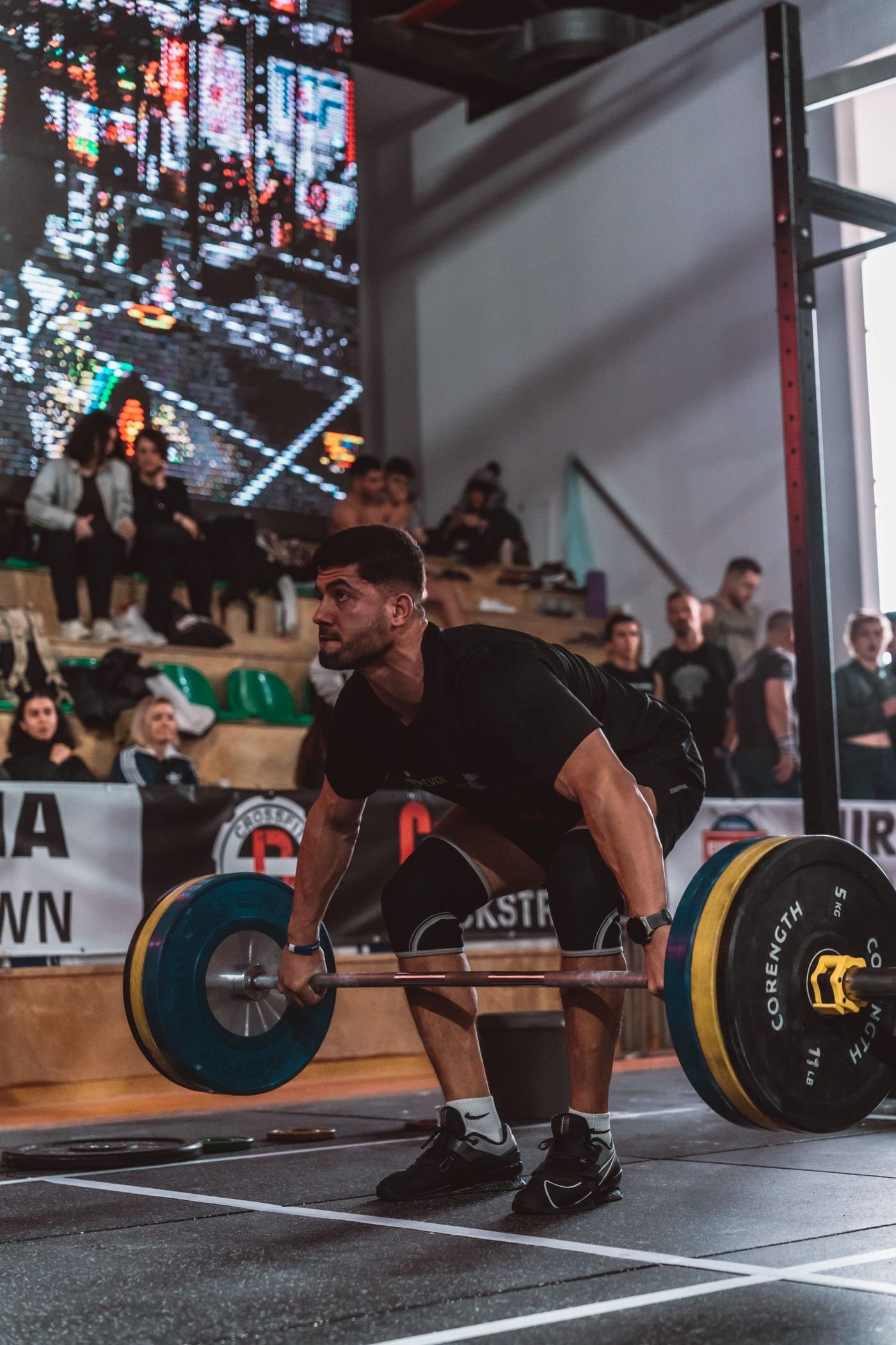 Athlete practicing a barbell deadlift in a busy gym
