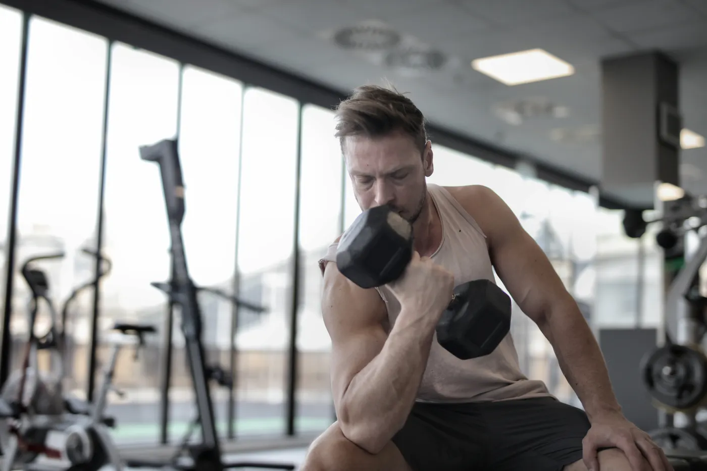 Man seated on a gym bench performing a dumbbell exercise