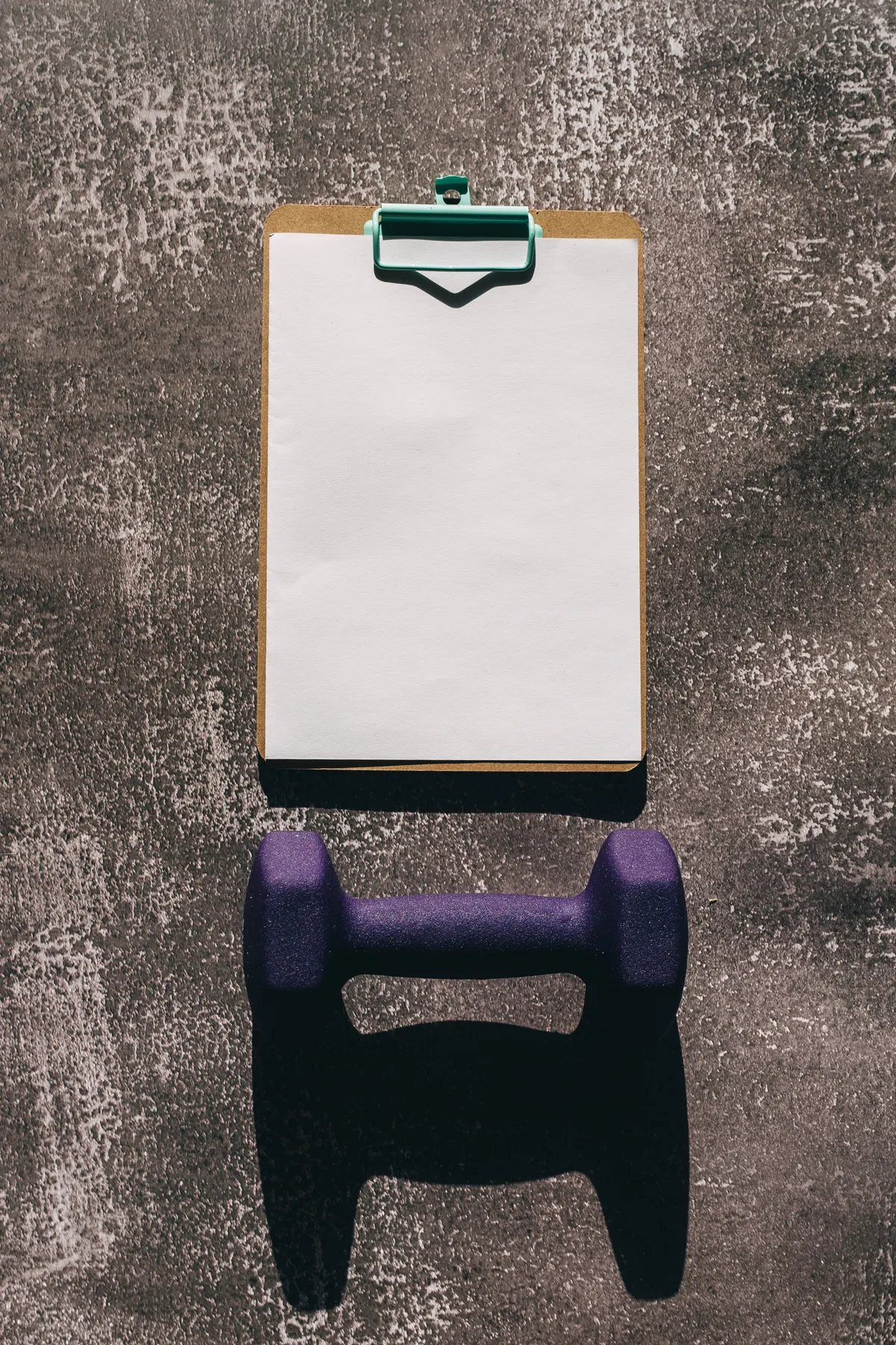 Dumbbell and clipboard representing a workout plan
