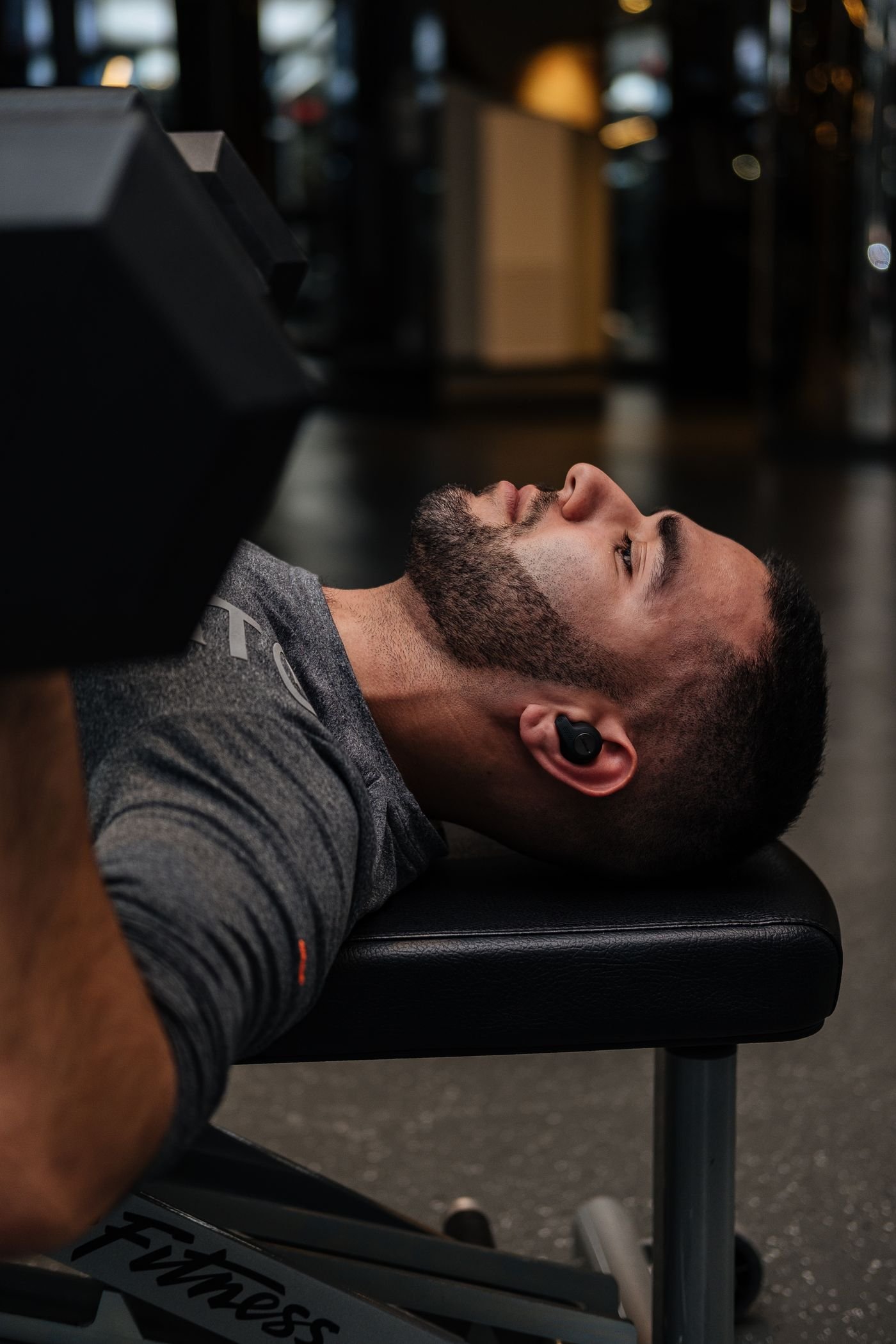 Man performing a dumbbell press on a weight bench