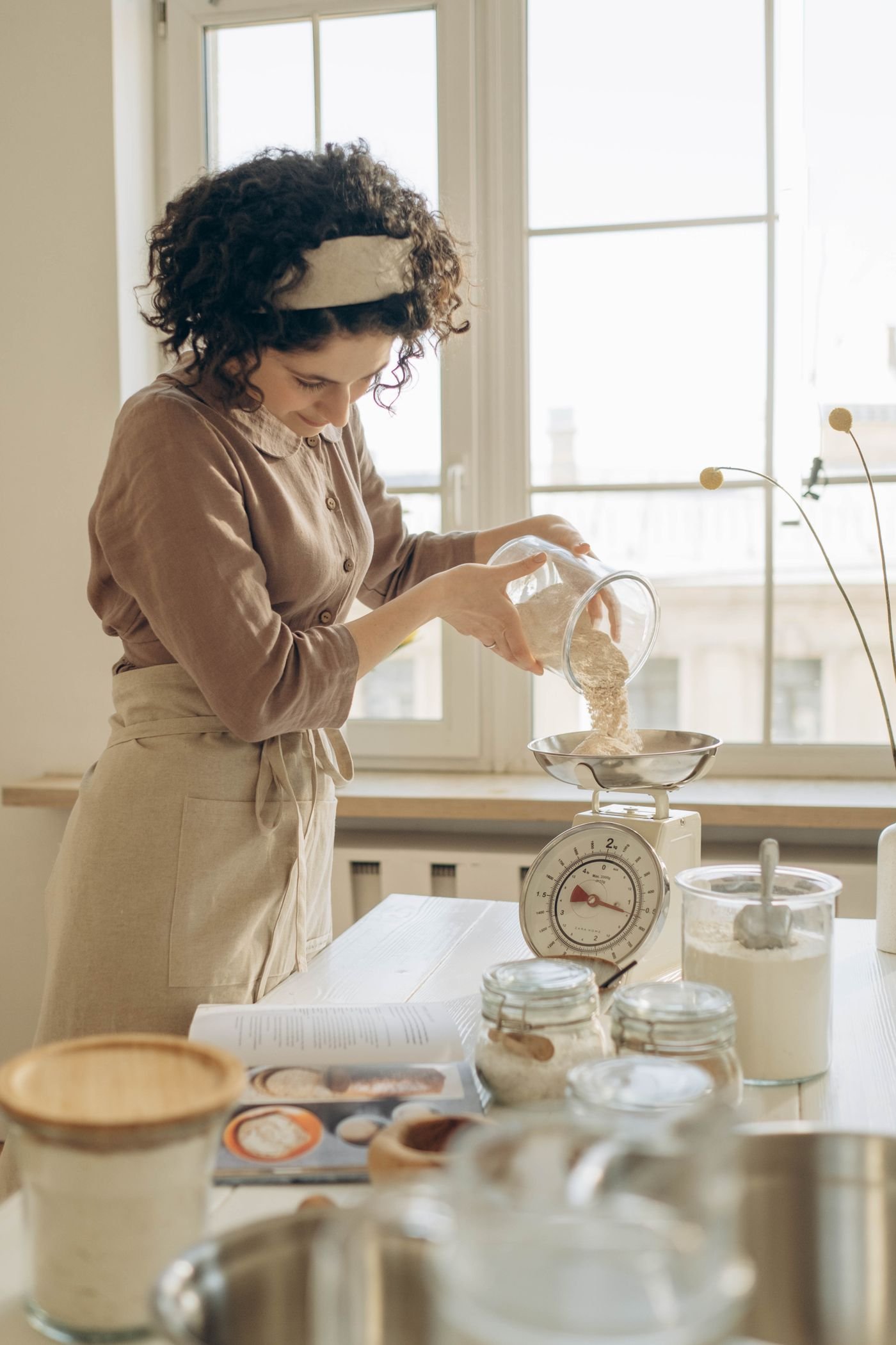 Person measuring ingredients on a kitchen scale while preparing a meal