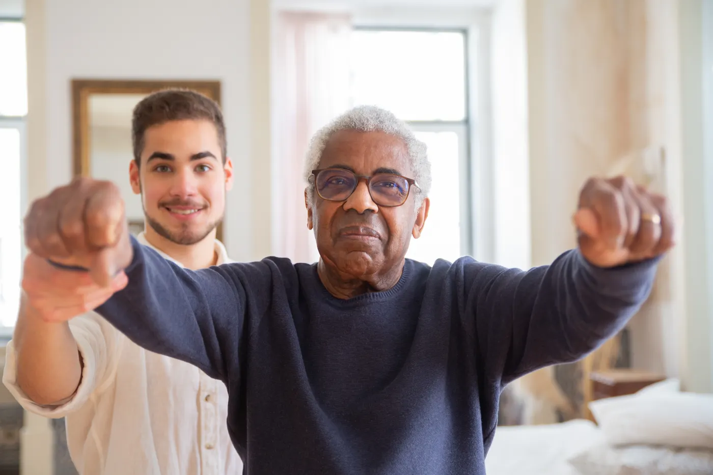 Older man practicing balance with assistance from a trainer