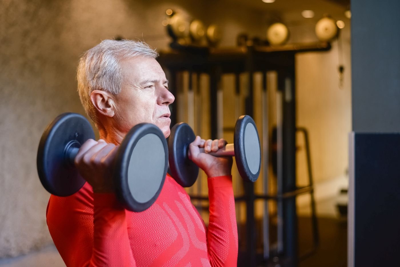 Older adult performing a dumbbell strength exercise in a gym